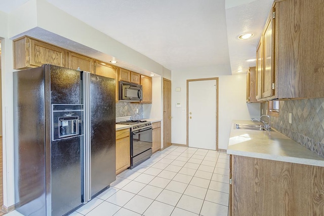 kitchen featuring light tile patterned floors, a sink, light countertops, decorative backsplash, and black appliances