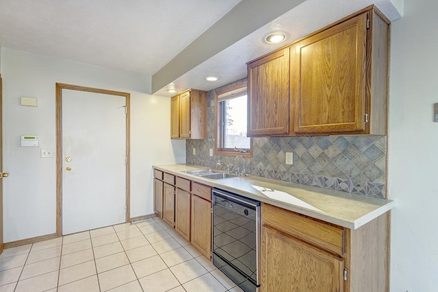 kitchen with black dishwasher, light countertops, a sink, and decorative backsplash