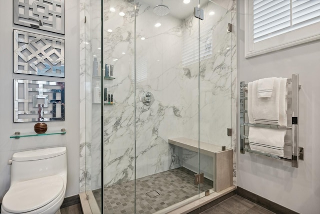 full bath featuring radiator heating unit, a marble finish shower, baseboards, and toilet