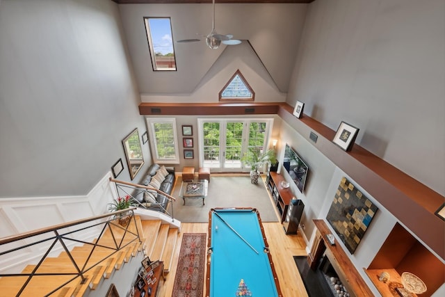 recreation room featuring visible vents, wainscoting, ceiling fan, wood finished floors, and high vaulted ceiling