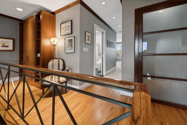 hall featuring baseboards, light wood-style flooring, and crown molding