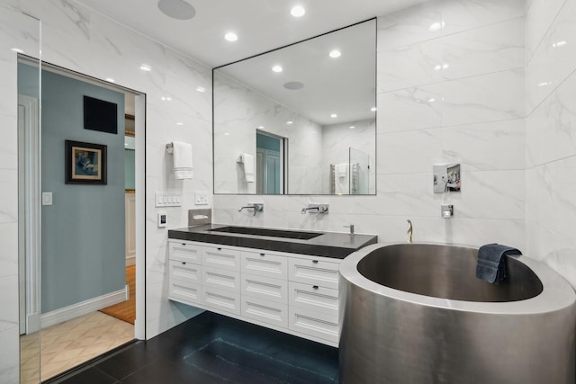 full bathroom with recessed lighting, a sink, tile walls, a soaking tub, and double vanity