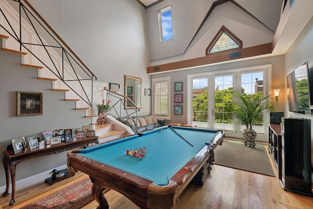 recreation room with a towering ceiling, billiards, baseboards, and wood finished floors