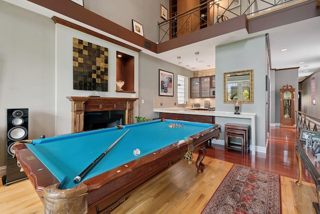 game room with a high ceiling, a fireplace, billiards, wood finished floors, and baseboards