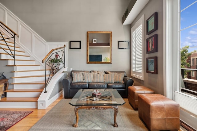 living area with stairway, wood finished floors, and a decorative wall