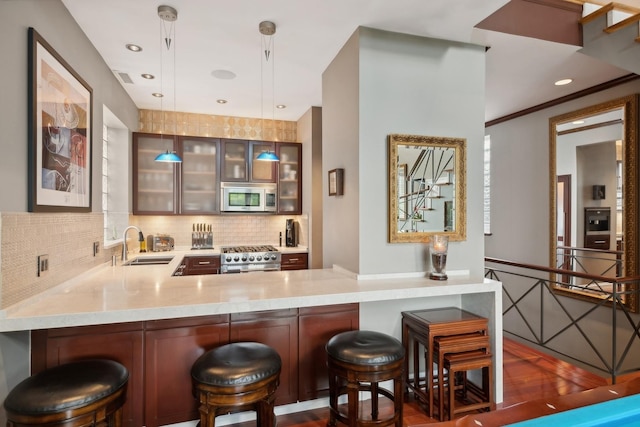 bar with pendant lighting, stainless steel microwave, decorative backsplash, stove, and a sink