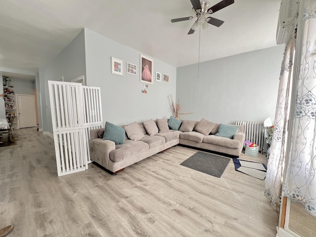 living area with radiator heating unit, a ceiling fan, and wood finished floors