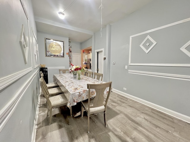 dining space featuring light wood-type flooring and baseboards