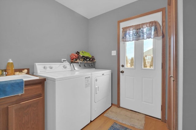 laundry room featuring cabinet space, light wood-style flooring, and washer and dryer