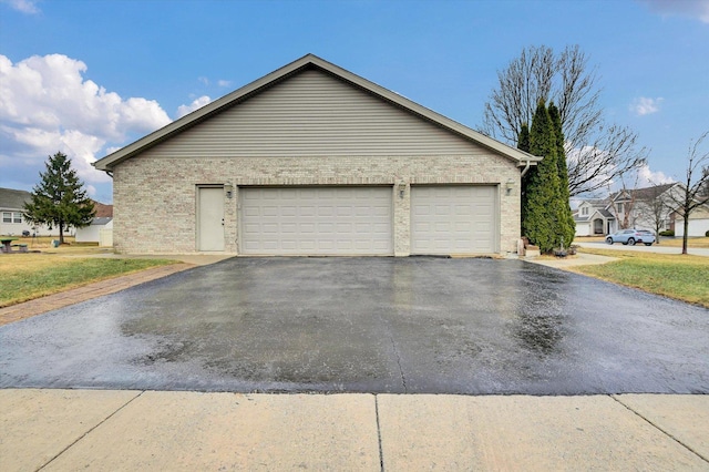 view of side of home featuring aphalt driveway and brick siding