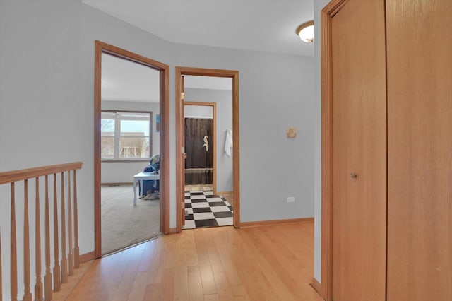 corridor with light wood-style floors and baseboards