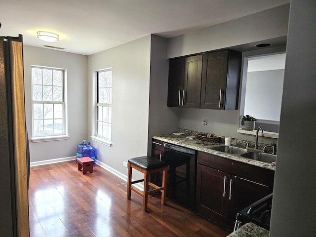 kitchen with baseboards, visible vents, dark wood-style floors, black appliances, and a sink