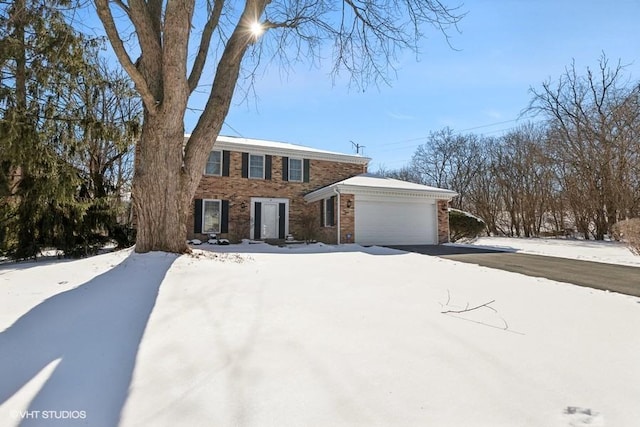 view of front of home with an attached garage, driveway, and brick siding