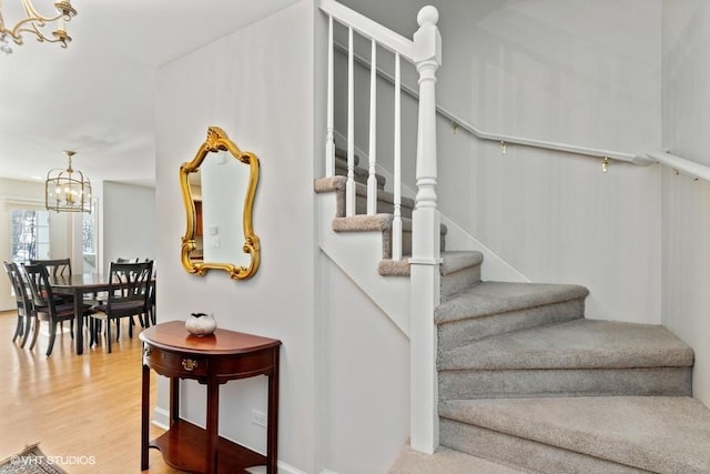 staircase featuring an inviting chandelier and wood finished floors