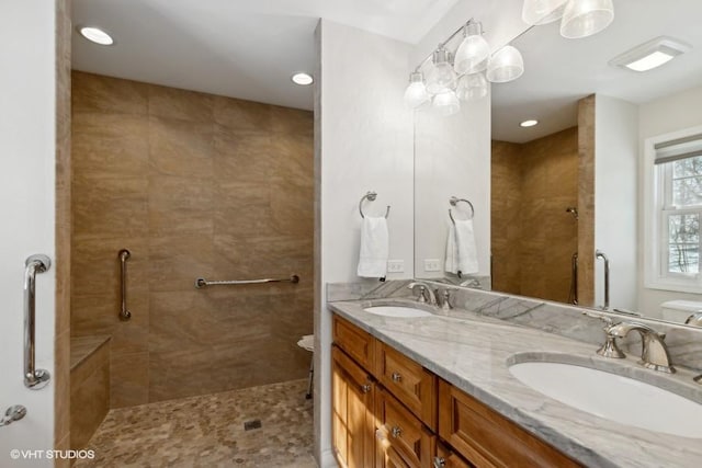 bathroom with double vanity, a tile shower, and a sink