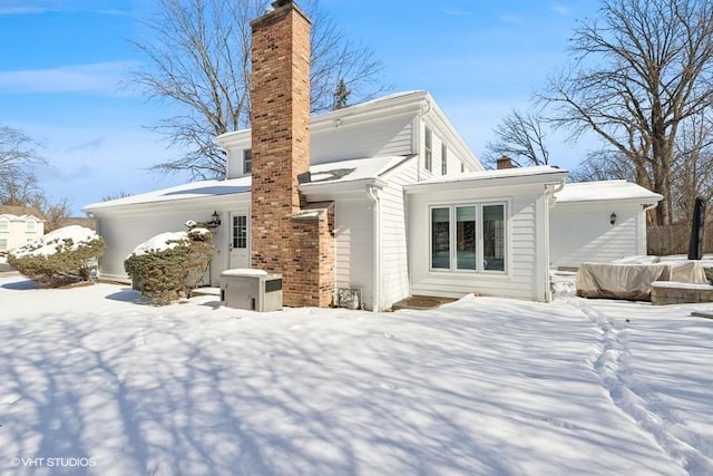 snow covered back of property with a chimney