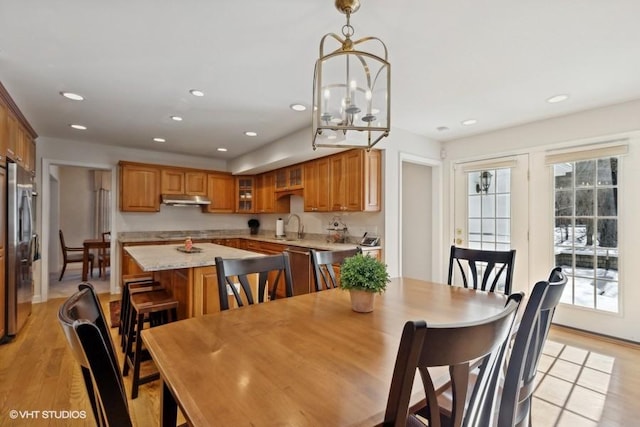 dining area with light wood-style floors, recessed lighting, and a notable chandelier