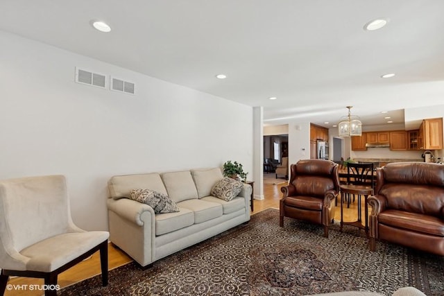 living room with an inviting chandelier, wood finished floors, visible vents, and recessed lighting