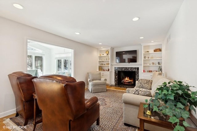 living area featuring recessed lighting, baseboards, visible vents, and a high end fireplace