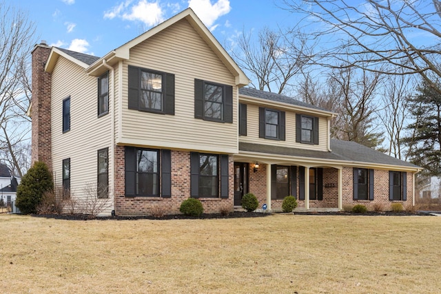 view of front of home with brick siding, a chimney, and a front lawn