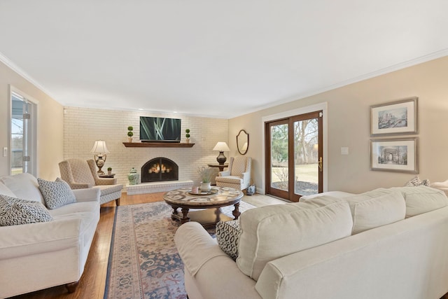 living area with brick wall, a fireplace, wood finished floors, and crown molding