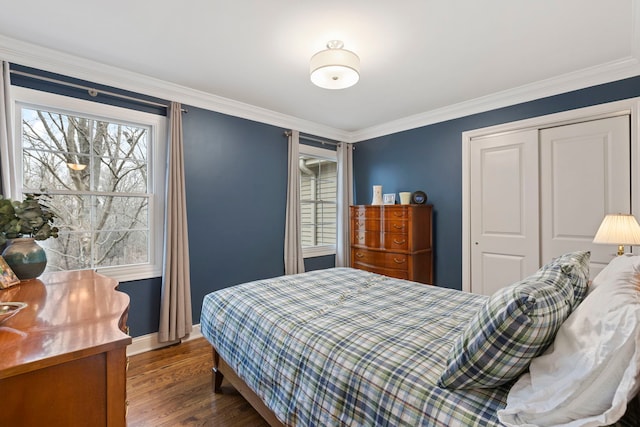 bedroom with crown molding, baseboards, a closet, and wood finished floors