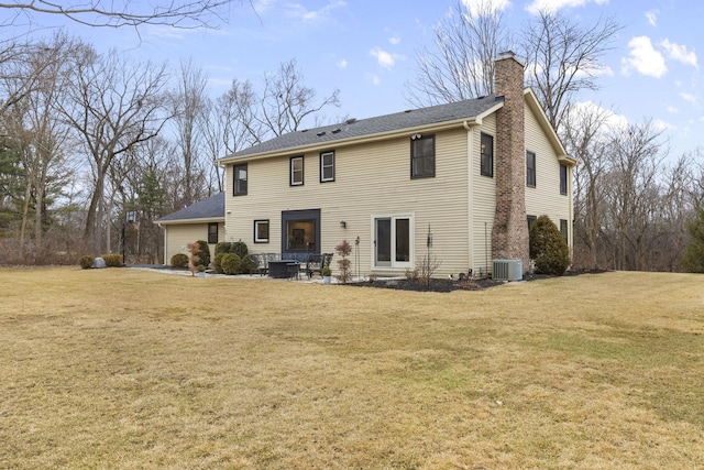 back of house with a shingled roof, central AC, a yard, and a chimney