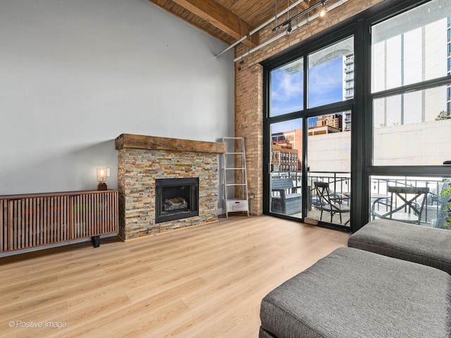 living area featuring a towering ceiling, wooden ceiling, wood finished floors, beamed ceiling, and a fireplace