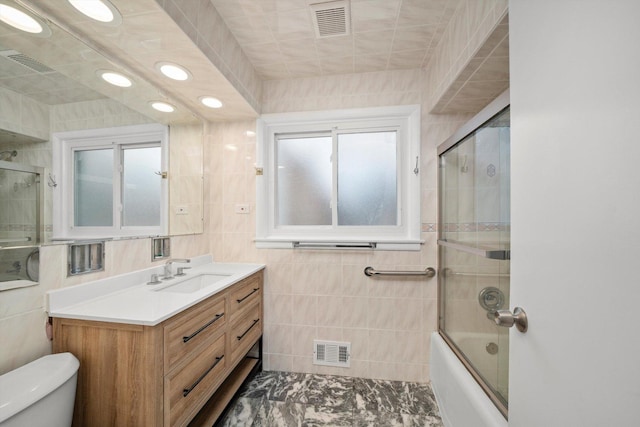 bathroom featuring visible vents, toilet, tile walls, and vanity