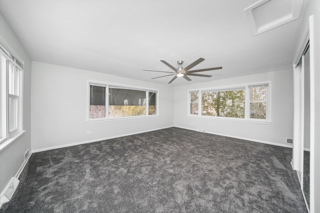 empty room with visible vents, baseboards, attic access, and dark carpet