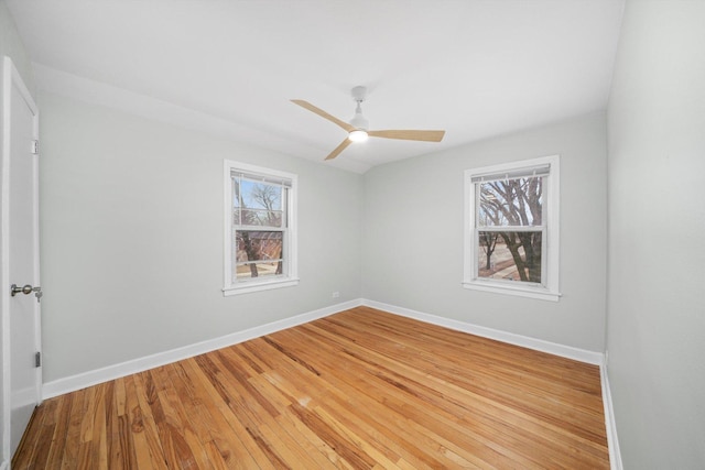 spare room with baseboards, light wood finished floors, and ceiling fan