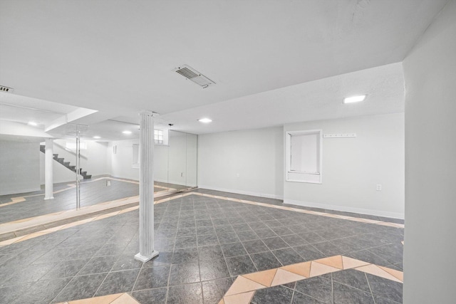 finished basement featuring visible vents, baseboards, dark tile patterned floors, stairs, and recessed lighting