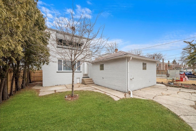 back of house featuring a lawn, brick siding, and a fenced backyard