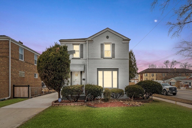 traditional-style home with fence, a lawn, and brick siding