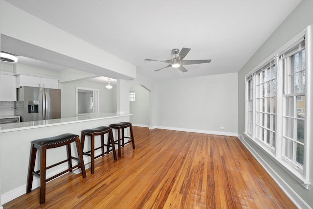 interior space featuring a breakfast bar, light countertops, wood finished floors, arched walkways, and stainless steel fridge