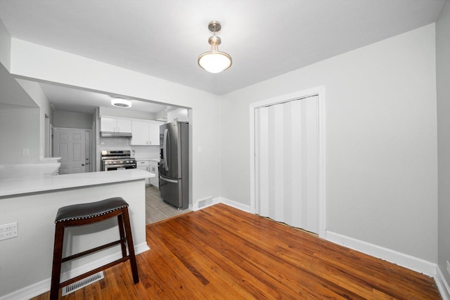 kitchen featuring visible vents, light countertops, appliances with stainless steel finishes, a peninsula, and white cabinetry