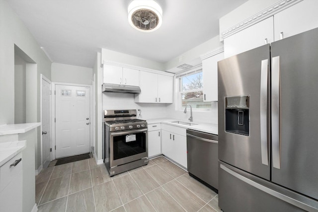 kitchen featuring under cabinet range hood, stainless steel appliances, light countertops, and a sink