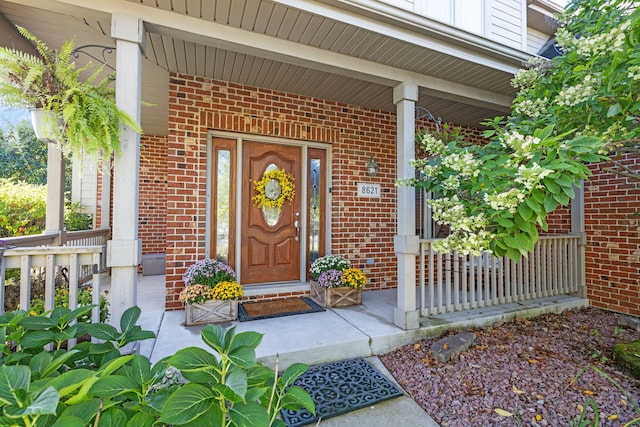 entrance to property with a porch and brick siding