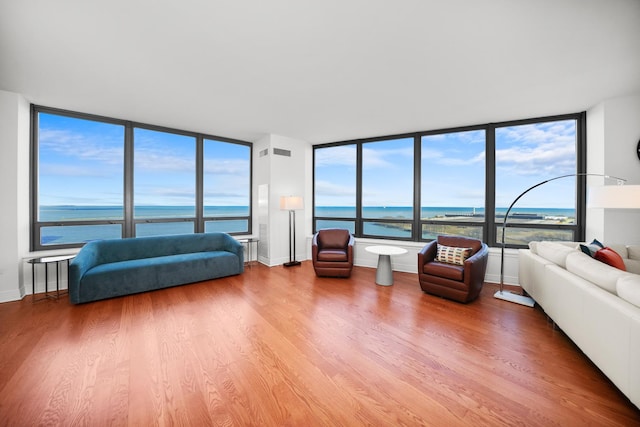 unfurnished living room with a water view, wood finished floors, visible vents, and baseboards