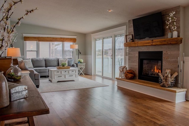5-124 Sunrise Ct, Lanark, IL 61046 - living area with a textured ceiling, a wainscoted wall, a fireplace, wood finished floors, and vaulted ceiling
