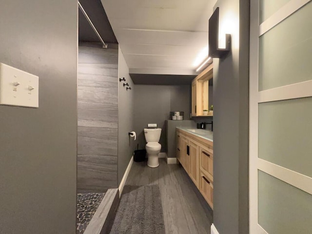 5-124 Sunrise Ct, Lanark, IL 61046 - bathroom featuring toilet, a tile shower, vanity, wood finished floors, and baseboards