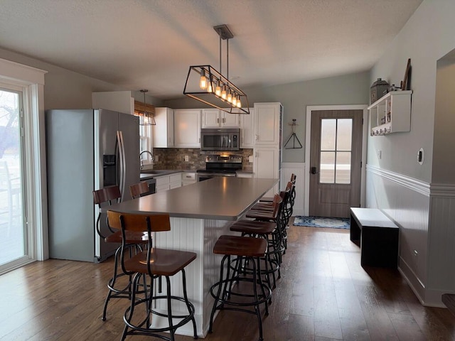 5-124 Sunrise Ct, Lanark, IL 61046 - kitchen featuring stainless steel appliances, a breakfast bar, a sink, white cabinets, and dark wood-style floors