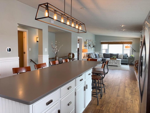 5-124 Sunrise Ct, Lanark, IL 61046 - kitchen with a breakfast bar, white cabinets, a center island, dark countertops, and dark wood finished floors