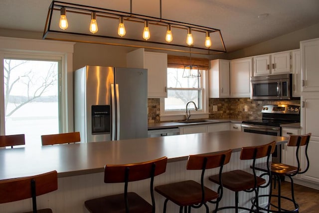 5-124 Sunrise Ct, Lanark, IL 61046 - kitchen featuring a sink, white cabinets, appliances with stainless steel finishes, backsplash, and a kitchen bar