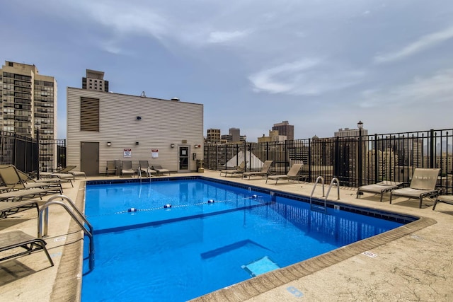 pool featuring a patio area, a view of city, and fence