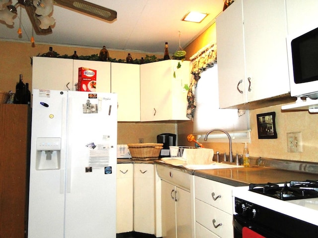 kitchen with dark countertops, white appliances, ceiling fan, and a sink