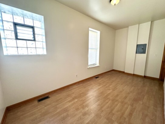 unfurnished room featuring a healthy amount of sunlight, light wood-style floors, electric panel, and visible vents