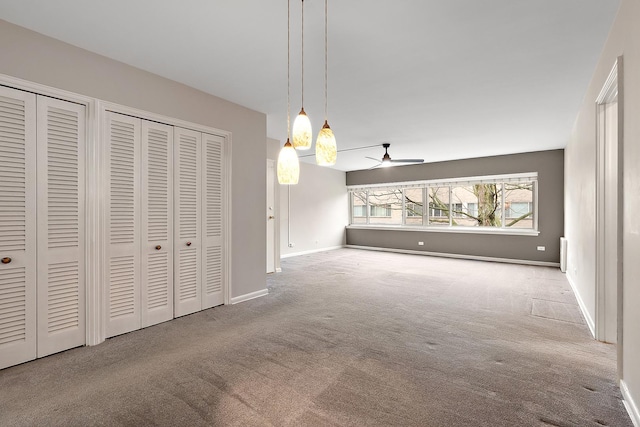 unfurnished dining area featuring carpet flooring, a ceiling fan, and baseboards