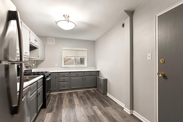 kitchen featuring gray cabinets, visible vents, appliances with stainless steel finishes, dark wood-type flooring, and baseboards