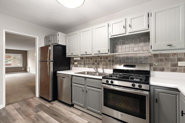 kitchen featuring a sink, light countertops, appliances with stainless steel finishes, gray cabinets, and light wood finished floors